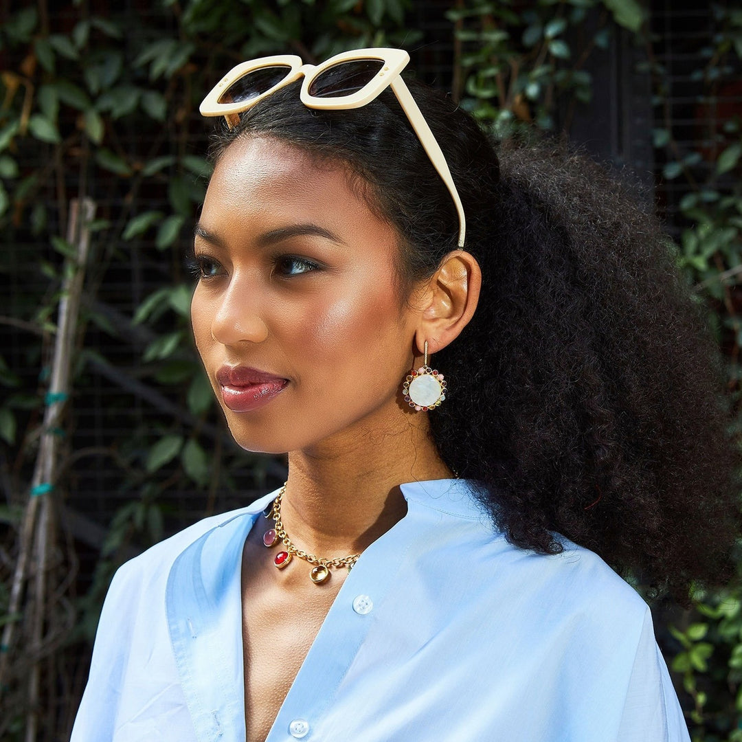 Laura Foote Designs mother of pearl drop earrings on a girl with light blue shirt.