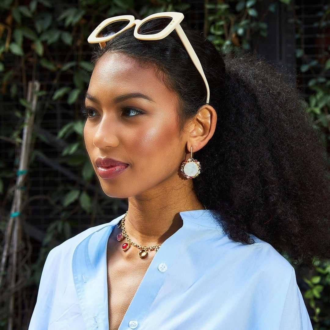 Laura Foote Designs luxury colorful Roy G Biv gold charm necklace on girls in blue shirt with pearl earrings.