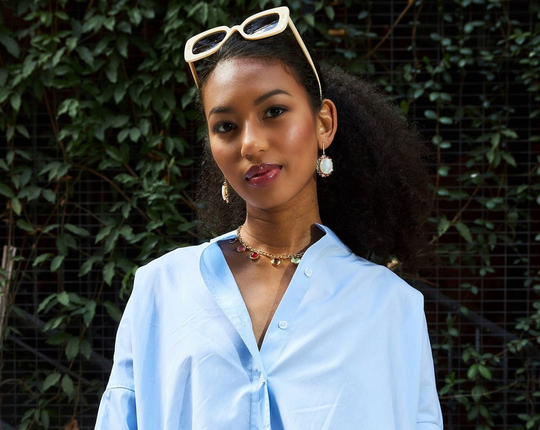 Girl with mother of pearl and pave diamond statement earrings and gemstone charm necklace. 